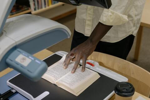 Student scanning a book in the library.